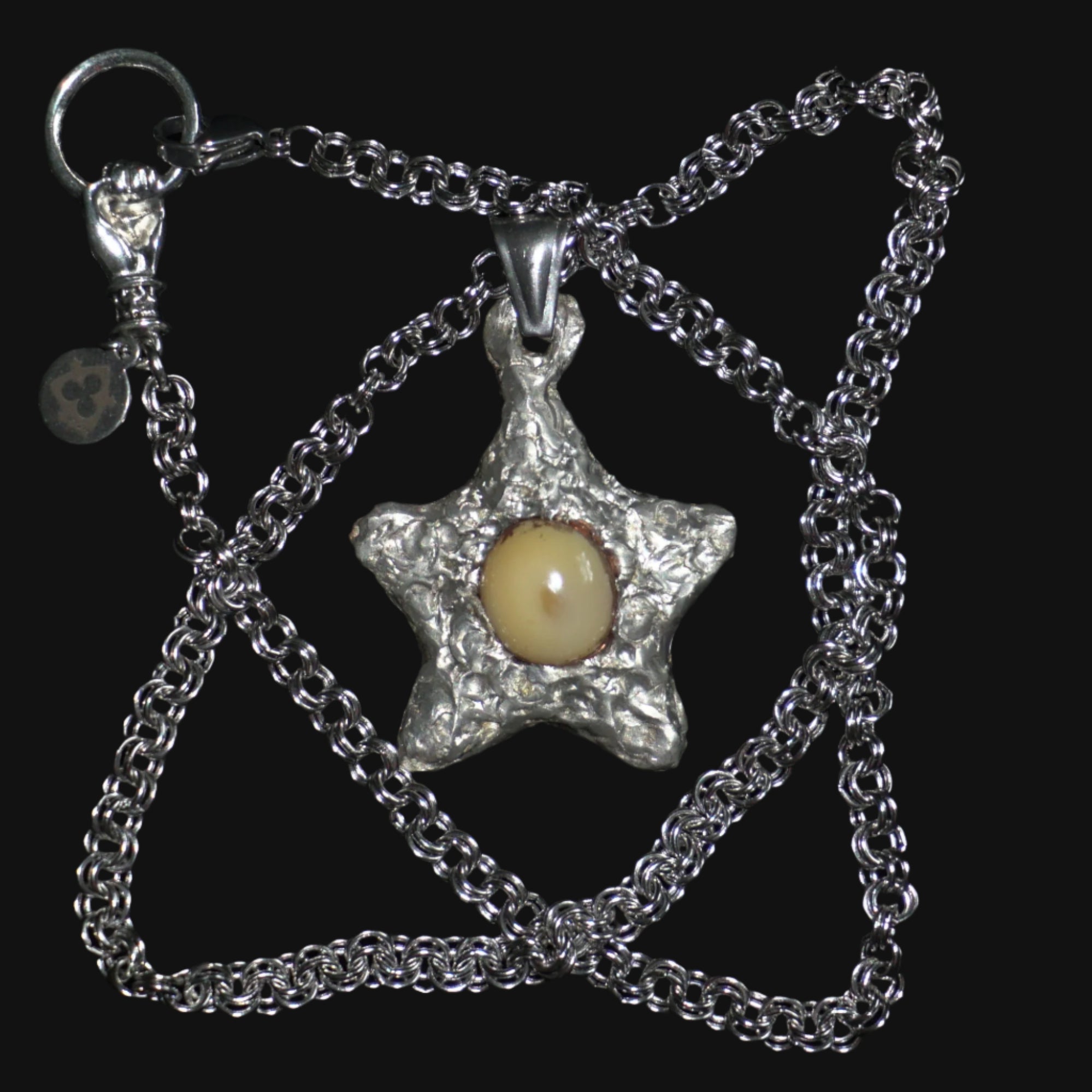 Star-shaped pendant with a central yellow opal on a chain against a black background