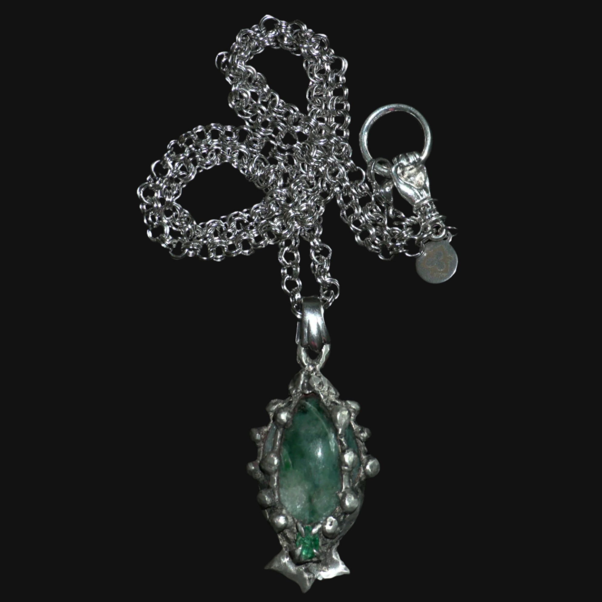 Silver pendant with a emerald gemstone on jade on a black background